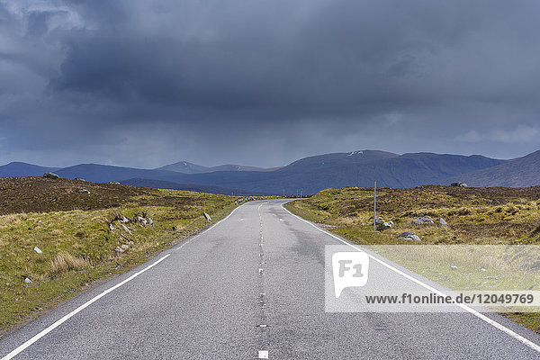 Landstraße mit dunkel bewölktem Himmel in den Highlands auf der A82 in Glen Coe  Schottland  Vereinigtes Königreich