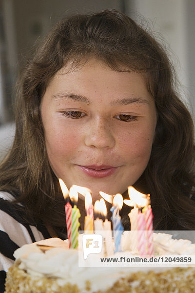 Mädchen bläst Kerzen auf Geburtstagskuchen aus