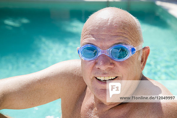 Porträt eines Mannes im Schwimmbad  der eine Schwimmbrille trägt