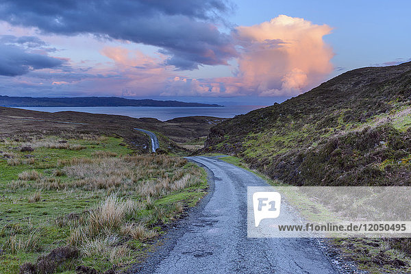 Old winding single track road in spring with cumulonimbus clouds at sunset on the Isle of Skye in Scotland  United Kingdom