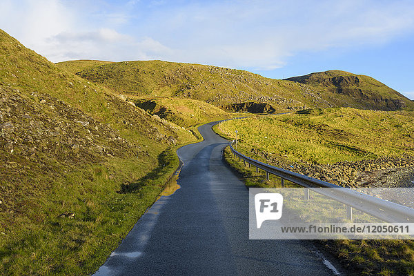 Typical Scottish landscape on the Isle of Sky with a coastal road and grassy hills in Scotland  United Kingdom