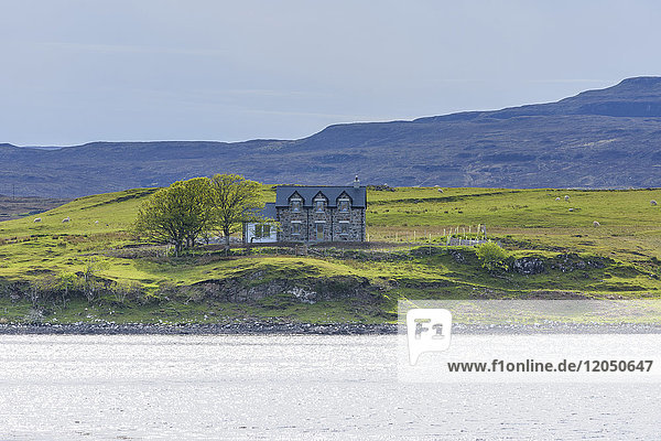 Meeresbucht mit typisch schottischem Wohnhaus in dem Dorf Dunvegan auf der Isle of Skye in Schottland  Vereinigtes Königreich