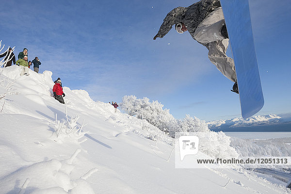 Snowboarder making a jump on a hillside  Homer  Southcentral Alaska  USA