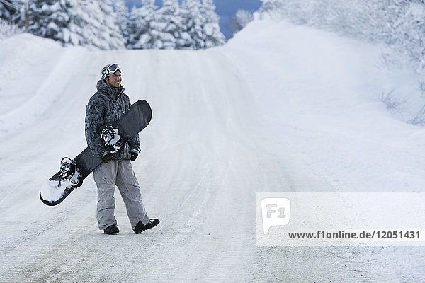 Snowboarder crossing a snow-covered road  Homer  Southcentral Alaska  USA