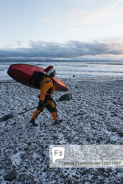Kajaksurfer mit Paddel und Kajak im Winter an der schneebedeckten Küste  Homer  Southcentral Alaska  USA