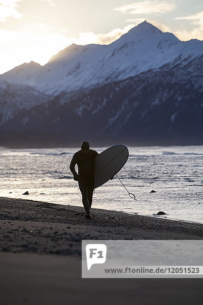 Surfer mit seinem Surfbrett in der Kachemak Bay  Homer Spit  Southcentral Alaska  USA