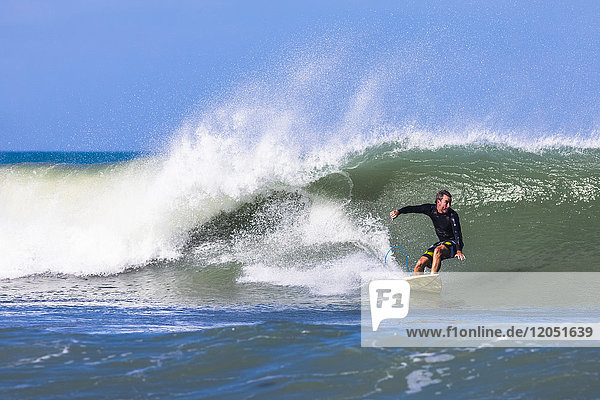 Ein Surfer reitet auf einer Welle am Pelican Beach am Atlantischen Ozean in Florida; Satellite Beach  Florida  Vereinigte Staaten von Amerika