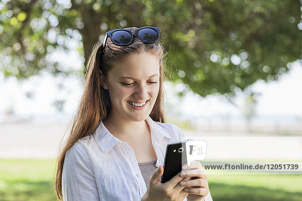 Teenage girl using her smart phone  Woodbine Beach; Toronto  Ontario  Canada