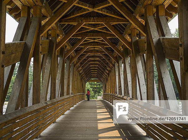Ein Paar steht am Ende einer überdachten Holzbrücke; Golden  British Columbia  Kanada