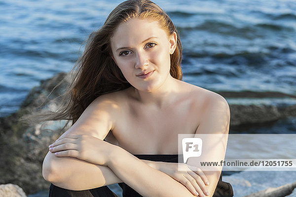 Portrait of a teenage girl sitting on rocks at Woodbine Beach in summer; Toronto  Ontario  Canada