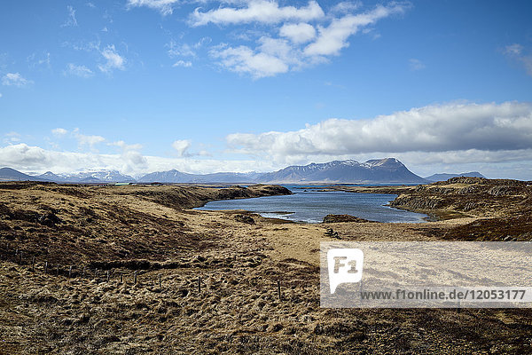 Braune Landschaft entlang der Küste mit Berggipfeln in der Ferne  Halbinsel Snaefellsnes; Island