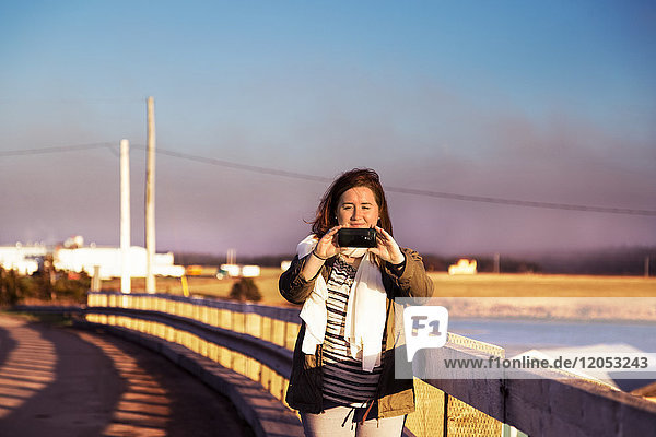 Eine Frau steht und macht ein Bild mit ihrer Smart Phone Kamera; Prince Edward Island  Kanada
