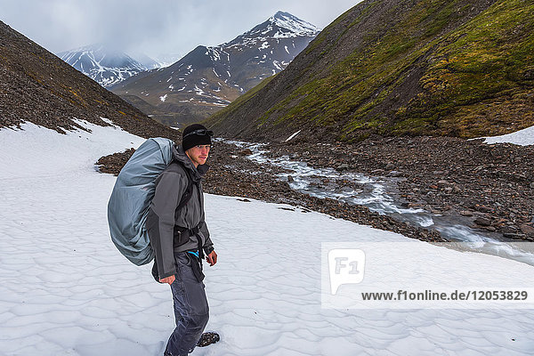 A backpacker trudges through snow while hiking over an unnamed pass in the Brooks Range at 1:33 a.m.; Alaska  United States of America
