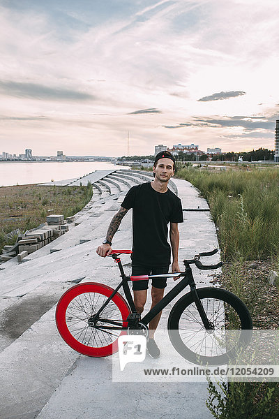 Portrait of young man with fixie bike at sunset