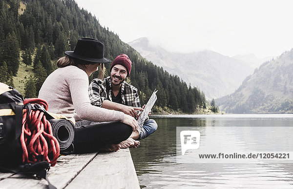 Austria  Tyrol  Alps  couple with map sitting on jetty at mountain lake