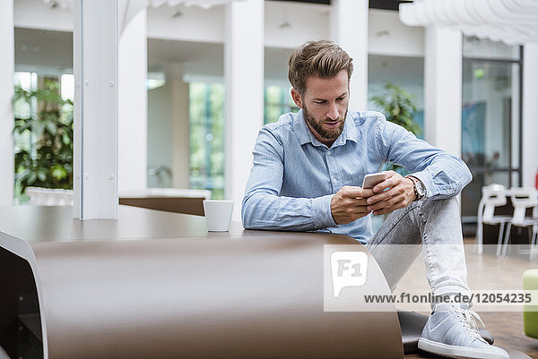 Mann mit Handy im modernen Büro