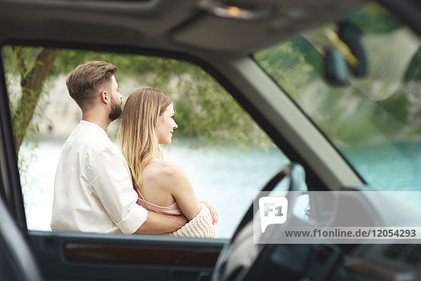 Young couple outside car looking at view
