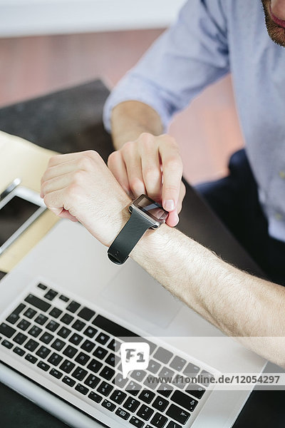 Young businessman working in office looking at smartwatch