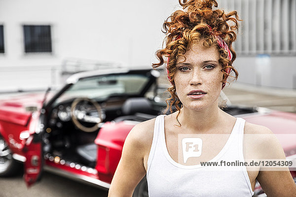 Porträt einer rothaarigen Frau am Sportwagen