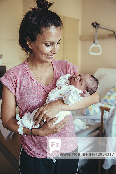 Glückliche Mutter die ihr neugeborenes Baby im Krankenhaus hält