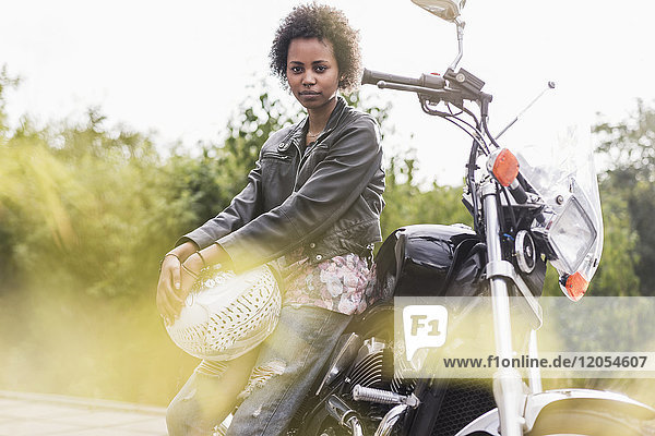 Porträt einer jungen Frau mit ihrem Motorrad