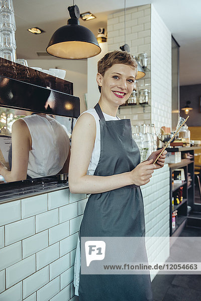 Portrait of smiling waitress holding menu in a cafe