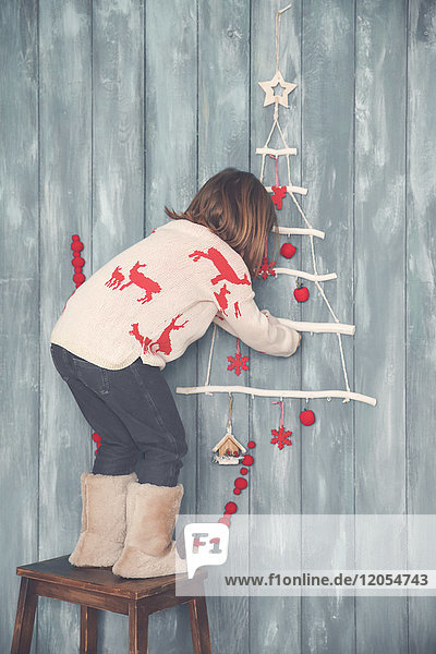 Kleines Mädchen schmückt die Wand zur Weihnachtszeit
