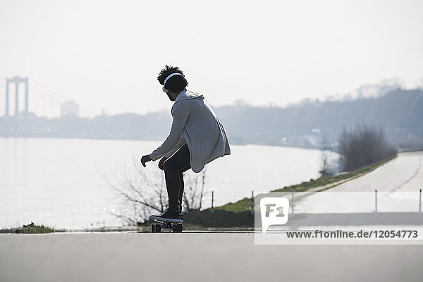 Young man riding longboard at the riverside