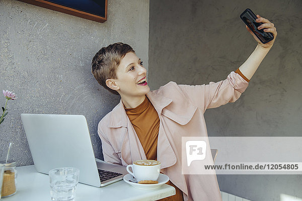 Frau  die einen Selfie mit ihrem Laptop in einem Cafe nimmt