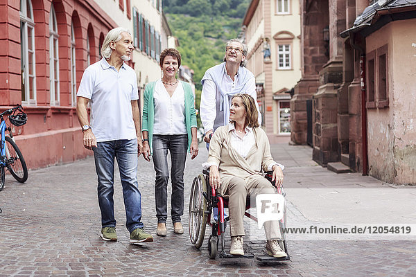 Deutschland  Heidelberg  Seniorenfreunde mit Frau im Rollstuhl auf Städtereise