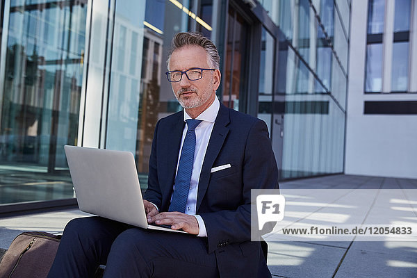 Portrait eines Geschäftsmannes mit Laptop im Freien