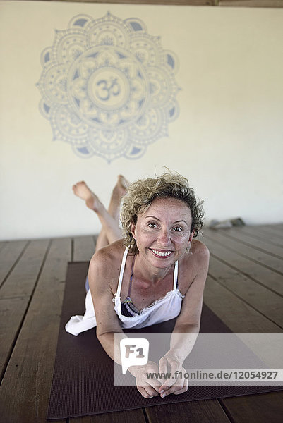 Porträt einer lächelnden Frau auf Yogamatte liegend