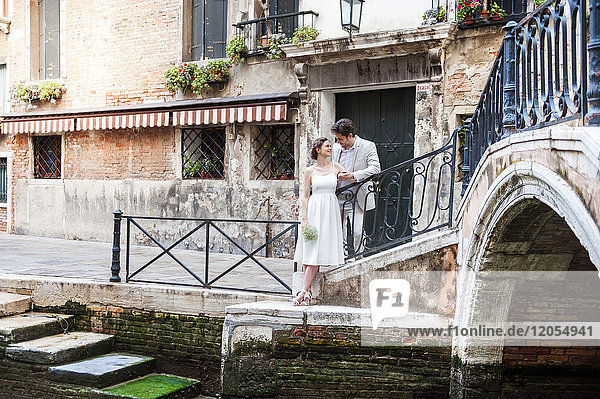 Italy  Venice  bridal couple standing face to face at canal
