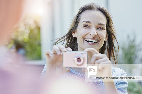Happy woman taking picture of her husband outdoors