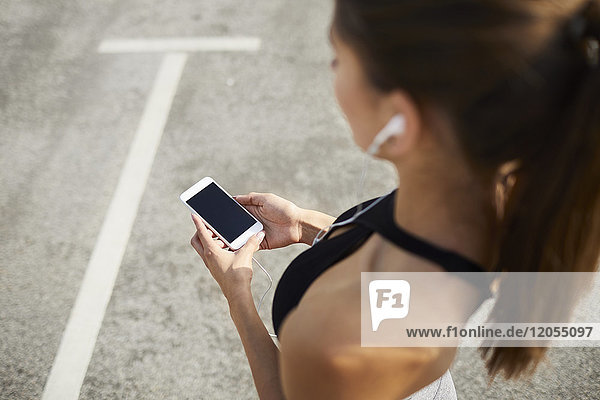 Nahaufnahme der Frau mit dem Smartphone während des Trainings