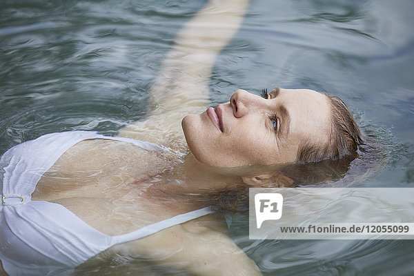 Porträt einer entspannten Frau  die auf dem Wasser schwebt