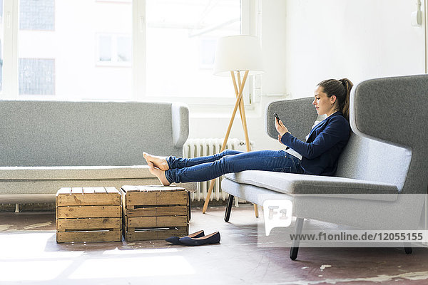 Businesswoman sitting on couch using cell phone