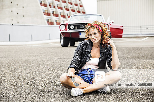 Portrait of confident redheaded woman sitting on parking level