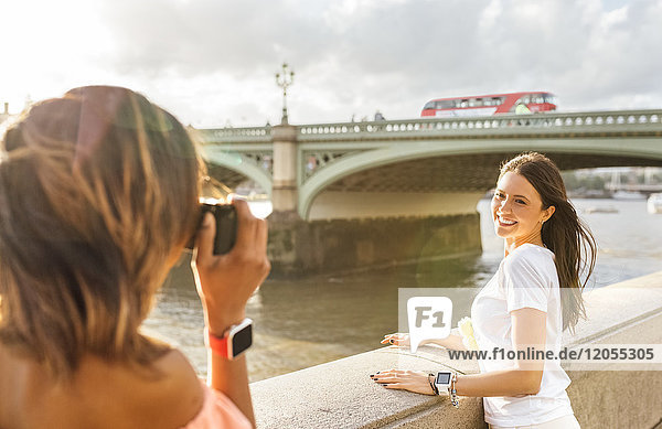 UK  London  woman taking a picture of her friend near Westminster Bridge