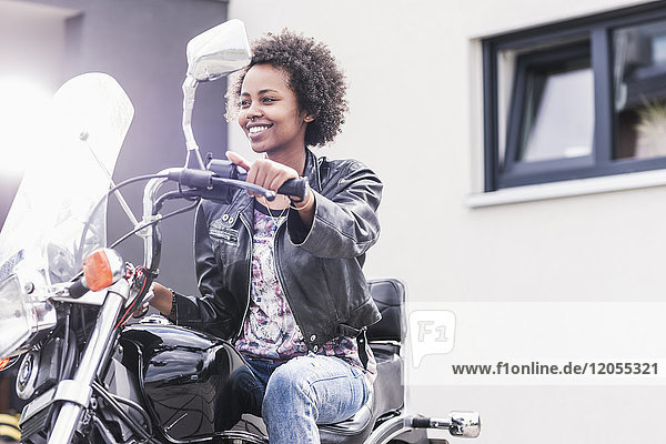 Lächelnde junge Frau auf ihrem Motorrad