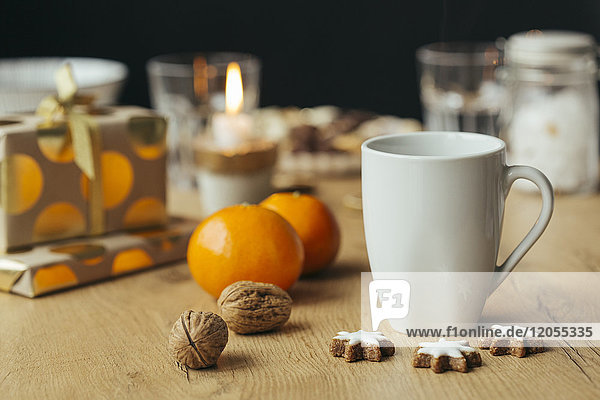 Tasse Tee  Mandarinen  Walnüsse  Zimtsterne und Weihnachtsgeschenke im Hintergrund