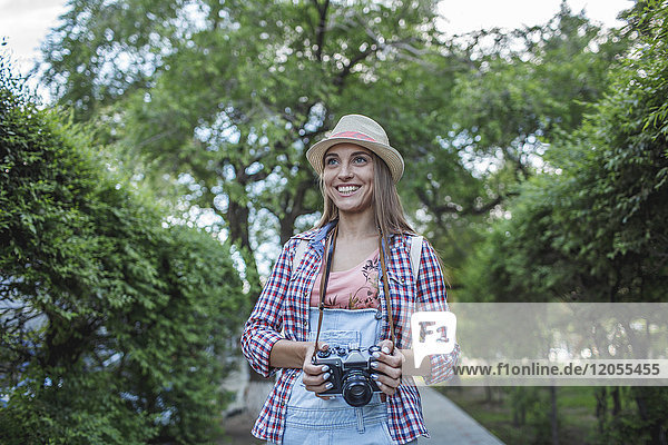 Smiling young woman with a camera in a park