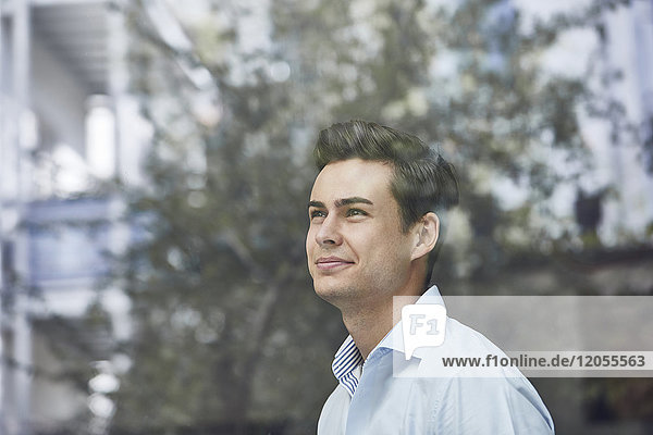 Portrait of smiling young businessman looking out of window