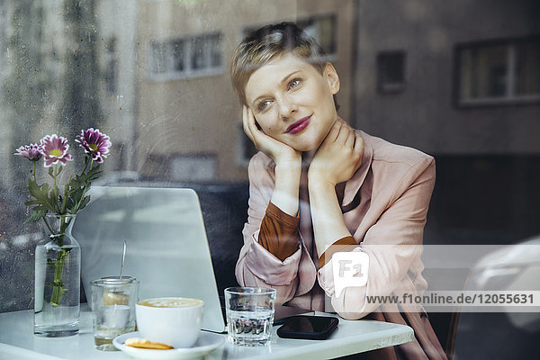 Frau mit ihrem Laptop genießt die Aussicht in einem Cafe