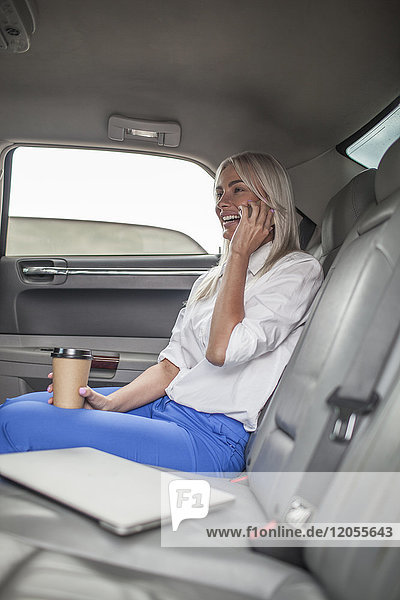 Glückliche Geschäftsfrau am Handy im Auto
