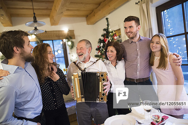 Senior Mann spielt Akkordeon für glückliche Familie an Weihnachten