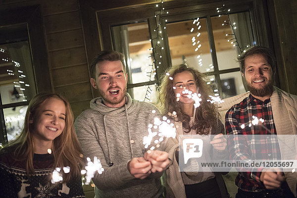 Happy friends holding sparklers outdoors at night