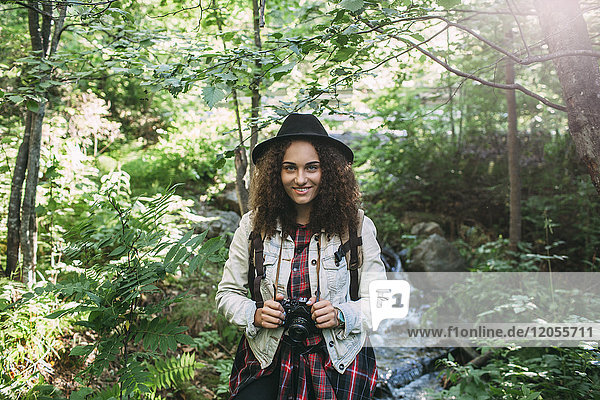 Portrait of smiling teenage girl with camera in nature