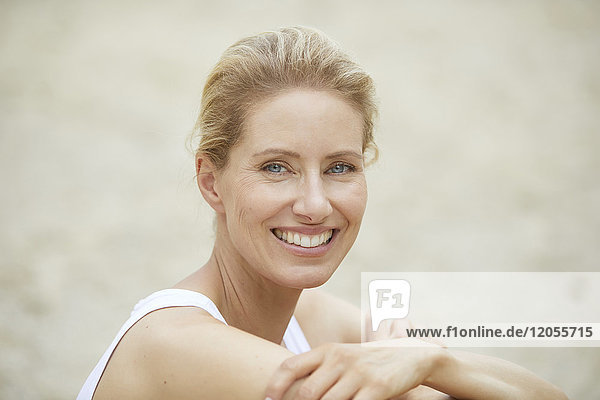 Porträt einer lachenden blonden Frau am Strand
