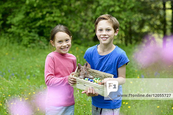 Portrait of little boy and girl holding Easter nest